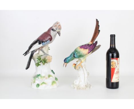 Two porcelain bird statues, one signed "Dresden" and the other with Capodimonte mark, depicting colorful birds surmounted on 