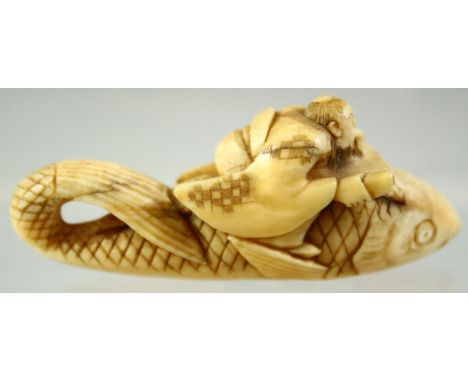 A JAPANESE CARVED IVORY NETSUKE of a seated deity on the back of a giant fish, signed to the base, 5.5cm long.