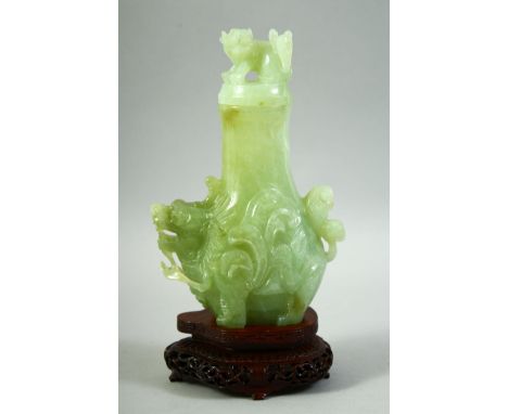 A CHINESE CARVED JADE VASE AND COVER on a fitted hardwood stand, the vase carved with foo dogs, overall height 25cm.