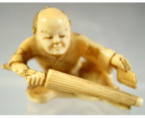 A JAPANESE CARVED IVORY NETSUKE of a seated man with a parasol in right hand and brush in his left, 5cm wide.