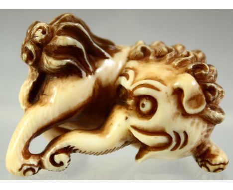 A JAPANESE CARVED IVORY NETSUKE of an elephant like beast, signed to the reverse, 4cm long.