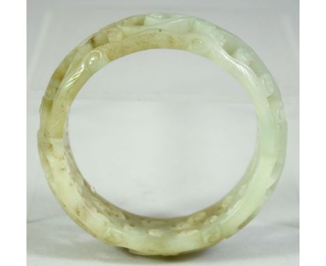 A CHINESE CARVED AND PIERCED JADE BRACELET, 8cm diameter.