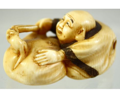 A JAPANESE CARVED IVORY NETSUKE of a seated man playfully teasing a mouse in a basket, signed to the base, 4.5cm wide.