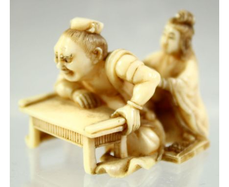 A JAPANESE CARVED IVORY NETSUKE of a man leaning on a table; his back being massaged by a young lady, signed to base, 3.5cm l