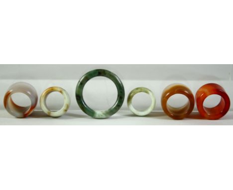 FIVE GOOD AGATE AND JADE / JADEITE ARCHER'S RINGS, together with a larger jade / jadeite ring, (6).