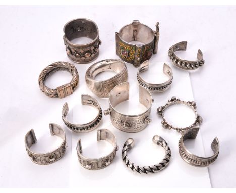 A collection of twelve Indian and Bedouin tribal bangles, of various designs including ropework, chase engraved and applied p