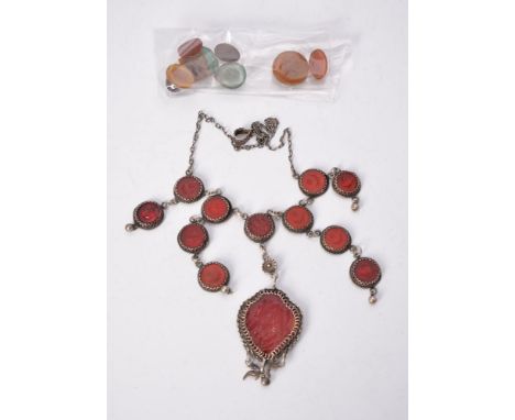 An Islamic glass intaglio necklace, the red glass panel with Arabic script and a fringe of boteh shaped panels, suspended fro