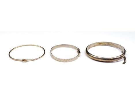 Two silver bangles and a plate example includes a childs bangle marked London 1957 WH and a hinged bnagle marked Sterling 925
