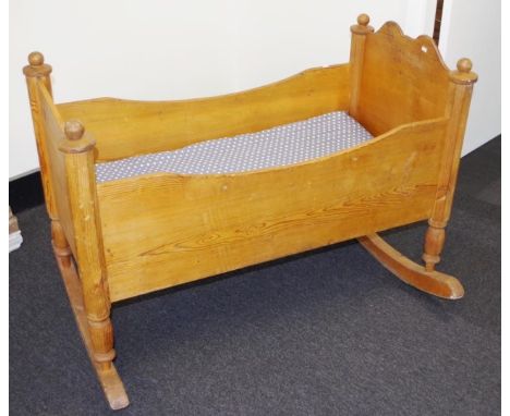 Vintage pine baby's crib/rocker with decorative finials and shaped ends, includes covered fitted mattress on wood base, and r