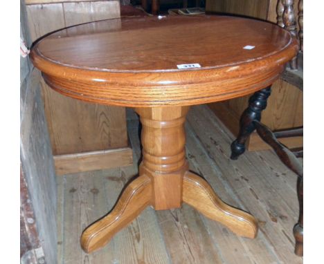 A 24" diameter modern varnished oak pedestal table, set on heavy turned pillar and tripod base