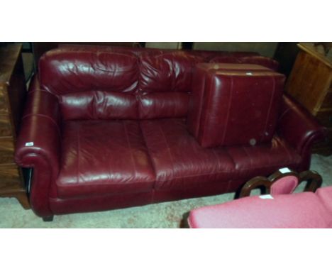 A 7' 3" modern three seater settee upholstered in oxblood coloured leather - sold with a locker pouffe