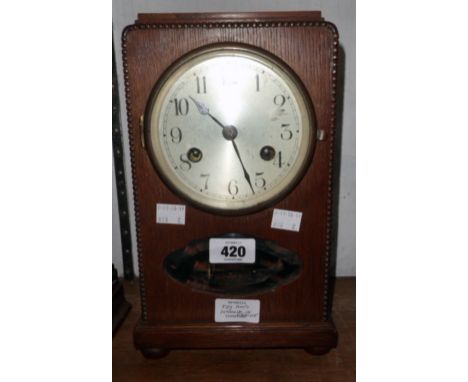 An early 20th Century oak cased mantel clock with silvered dial, visible pendulum and eight day gong striking movement
