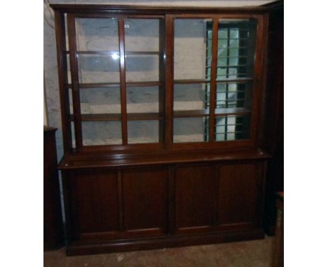 A 6' 3" early 20th Century mahogany two part book cabinet with two sets of adjustable shelves enclosed by a pair of glazed pa