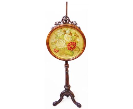 A 19th Century figured walnut pole screen with pierced pediment and decorative floral needlework panel under glass, set on tu