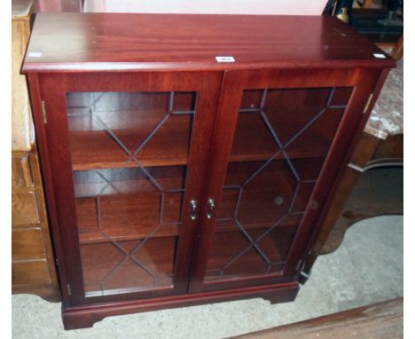 A 33" New Plan mahogany effect book cabinet enclosed by a pair of etched glazed panel doors, set on bracket feet