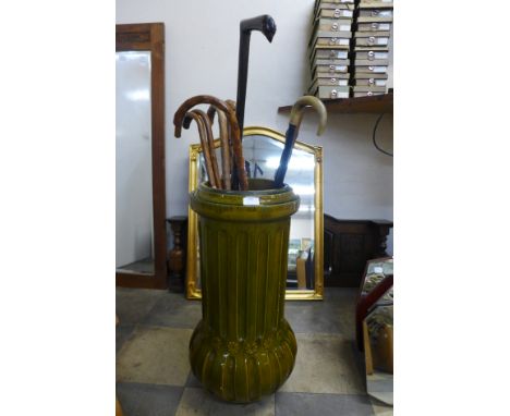 A Victorian green glazed walking stick stand and nine walking sticks 