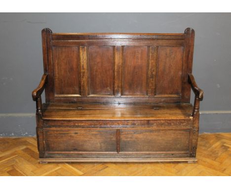 A George III oak settle with four panel back, rising seat, two panel box base on block feet, 114 x 47 x 137cm