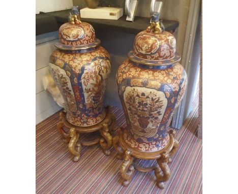 IMARI CERAMIC JARS, a pair, of inverted baluster form, the lids with Foo Dog finials, each with wooden stand, 108cm H overall