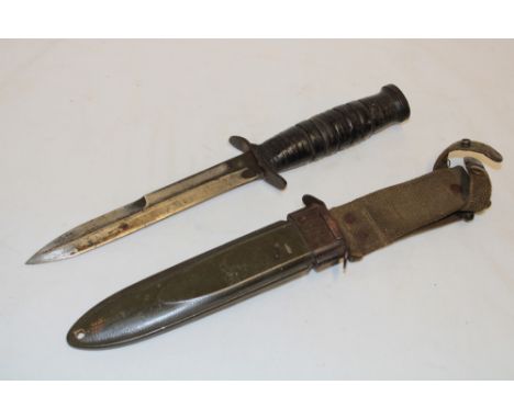 A United States M8 survival knife with single edged blade and leather grip in composition scabbard