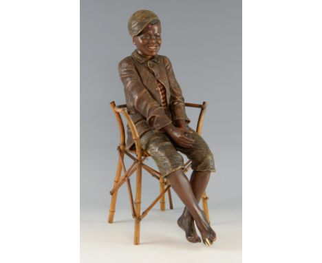 Friedrich Goldscheider, an Austrian painted terracotta figure of a young negro boy seated on a bamboo chair 50cm.      Condit