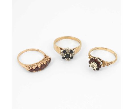 Three 9ct yellow gold gem set rings, including a garnet five-stone ring, garnet cluster ring, and a sapphire cluster ring, ri