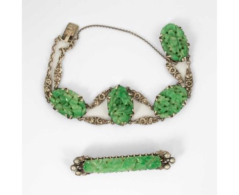 A jade set bracelet and brooch, the bracelet with four carved oval jade plaques joined by white metal flowerhead links, the b