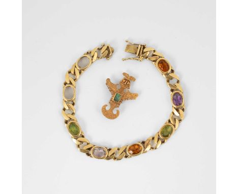 A yellow metal and emerald brooch of Aztec design, set with a step cut emerald, approximately 2.7cm long, stamped '18k', gros