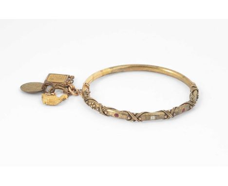 A yellow metal hinged bangle, set with a single old cut diamond and two rubies, rope twist and beaded detail, the safety chai