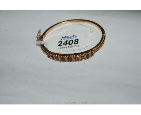 A pretty Edwardian unmarked gold Bangle set with diamonds between nine oval rubies (only eight stones present)