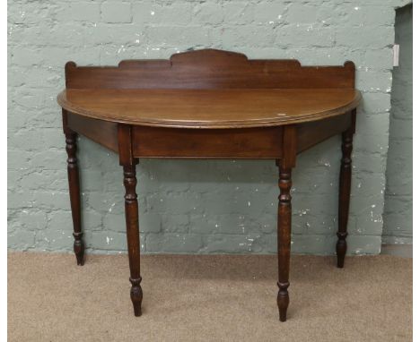 A Victorian mahogany demi lune console table raised on turned supports.