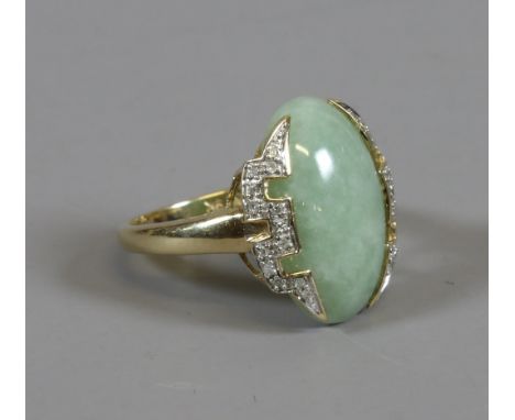 A 9ct gold ring set with an ovoid celadon jade table under Greek key diamond set, size Q.