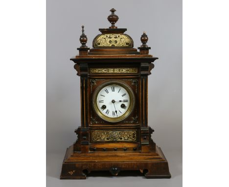 A continental oak and walnut eight day mantel clock with enamel dial and chiming half hourly on a gong.