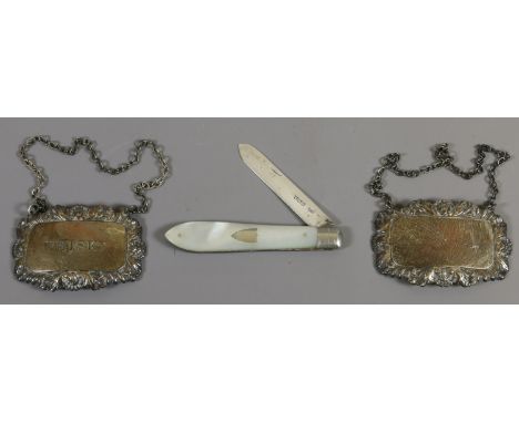 A silver and mother of pearl folding fruit knife Sheffield 1923 and two silver decanter labels Birmingham 1979 on engraved Wh