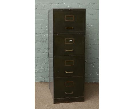 A vintage metal four drawer filing cabinet with brass handles.