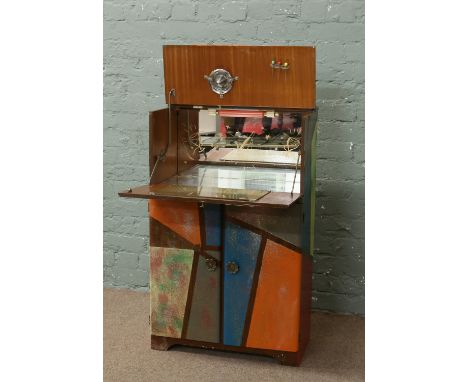 A walnut cocktail cabinet with clobbered decoration and a quality of glassware including decanter and Babycham glasses.