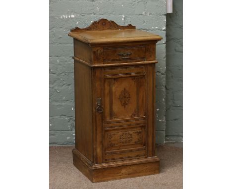 A light oak pot cupboard with carved decoration.