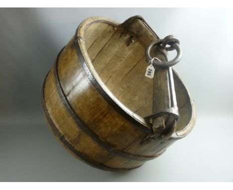 An Eastern wood and iron well bucket of barrel form with iron straps, timber and iron yoke style crossbar and iron tying ring