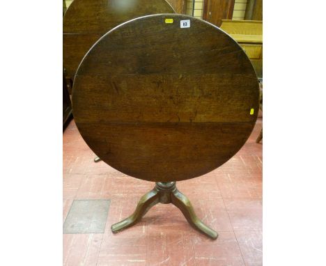 A circular oak tilt top tripod table with turned centre column and gently curved supports, 76 cms diameter