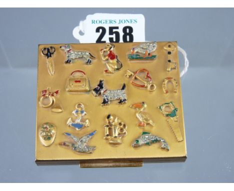 A yellow metal Foster lady's compact, the top lid encrusted with various animal, bird and other charms