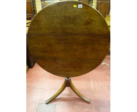 A circular oak tilt top tripod table with turned centre column and gently curved supports, 84 cms diameter