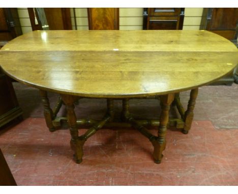 A substantial Cotswold made antique style oak drop leaf dining table with twin gate supports, of good colour having turned an