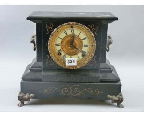A cast metal gilt highlighted mantel clock with lion mask ring handles and lion's paw metal corner mounts, Roman numeral enam