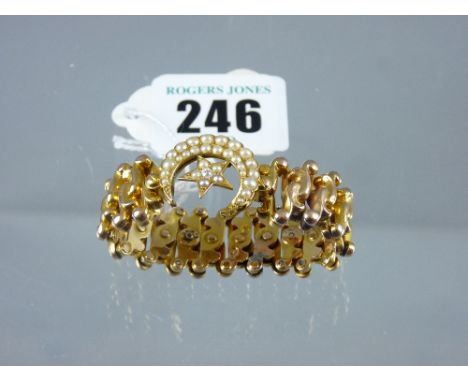A yellow metal expanding bangle having a centre crescent and star, each encrusted with graduated seed pearls