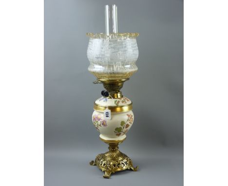 A Royal Worcester blush decorated and brass oil lamp, the pierced brass base with mask corners and twisted column surmounted 