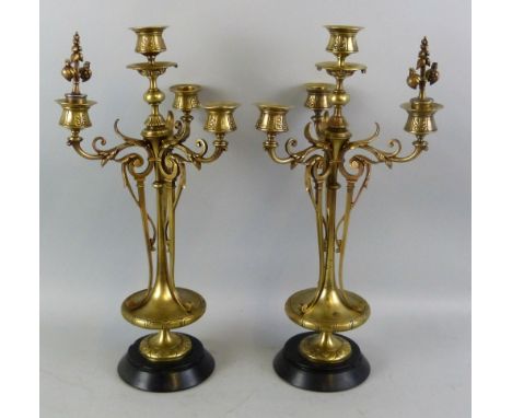 A pair of 19th century French brass four-light candelabra, each with tapering circular plate base, vase shaped central column