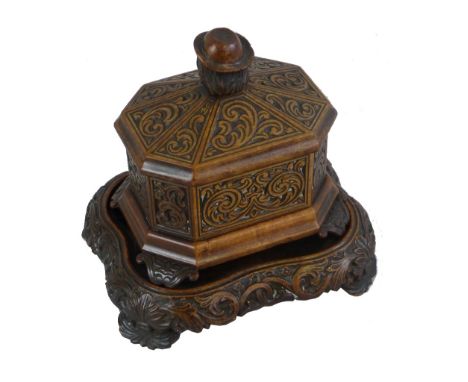 A Victorian Black Forest walnut tea caddy, of octagonal casket form carved all over with scrolling panels, the lift off domed
