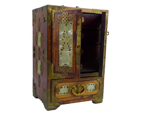 An Oriental hardwood table cabinet, of oblong form with chased yellow metal mounts, inset jade style pierced panels and brass