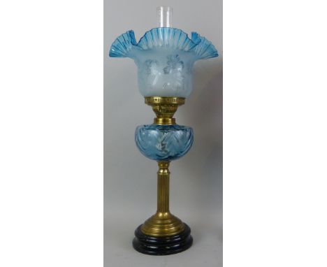 A Victorian style table oil lamp, with black glazed terracotta base supporting a reeded brass column, moulded blue glass rese