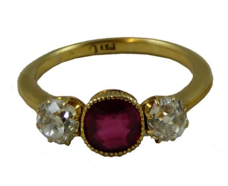 An Edwardian 18 ct gold, synthetic ruby and diamond three stone ring, reeded collet set with a mixed cut stone flanked by cla