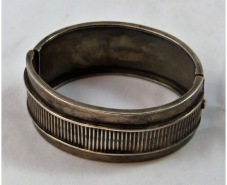 A Victorian silver hinged bangle, c 1880/1890, the front with an applied ribbed panel, internal width 6 cm, weight 34 grams.